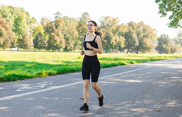 Athletic young happy woman runing in the park jogging in the morning for lifestyle health. Outdoor workout. Sport and healthy active lifestyle concept.