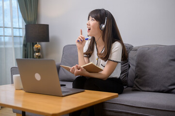 Beautiful young woman wearing headset is making video conference call via computer at home