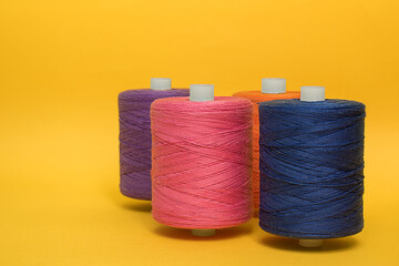 Multicolored spools of thread and yellow background