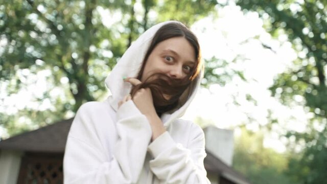 Beautiful woman in white hoodie looks at the camera and laughs