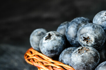 Fresh juicy blueberries in the bowl on the black background.
