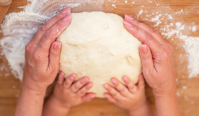 Grandmother and granddaughter using cookie cutter to cut dough in shapes. Little cute girl and...