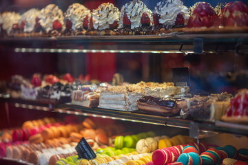 Different types of cakes in pastry shop glass display. Showcase with delicious sweets. French pastries on display a confectionery shop in France.