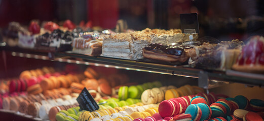 Different types of cakes in pastry shop glass display. Showcase with delicious sweets. French pastries on display a confectionery shop in France.