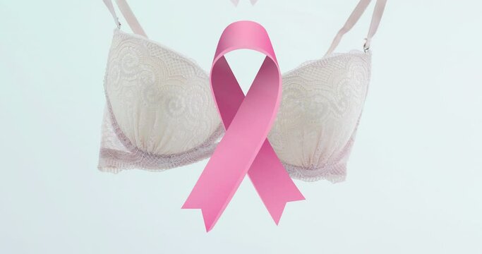 Animation of pink ribbon over bra on white background