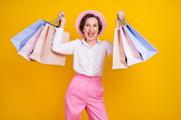 Photo of aged excited woman happy positive smile hold bags shop sale boutique isolated over yellow color background