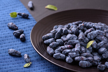 honeysuckle berry on a black round plate next to a blue napkin
