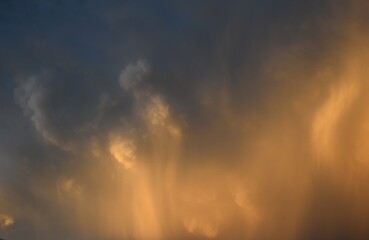 Naklejka na ściany i meble rain falling down from a cumulonimbus cloud with brigth sunligth