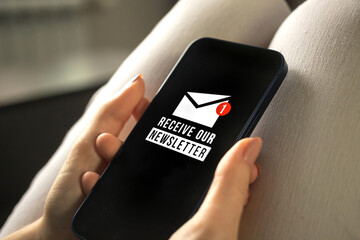Email marketing or newsletter concept, sending e-mails. Mobile phone with newsletter signup page close-up in woman hands