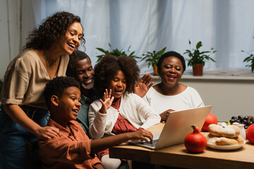 happy african american family waving hands during video call during thanksgiving dinner - obrazy, fototapety, plakaty