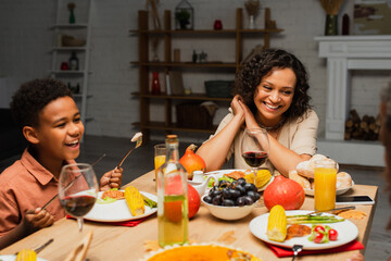 happy african american mother and son smiling during thanksgiving dinner