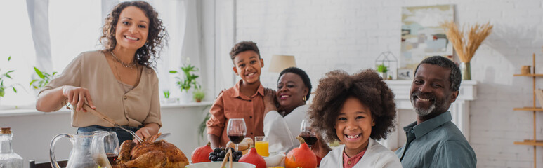 Smiling african american family near thanksgiving dinner at home, banner