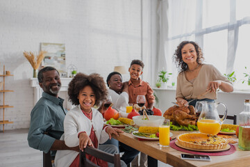 Smiling african american family celebrating thanksgiving with turkey at home