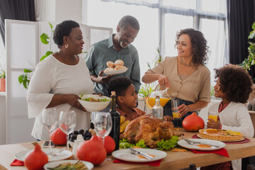 African american grandparents holding food near family and thanksgiving dinner - Powered by Adobe