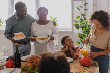 Smiling african american family serving thanksgiving dinner near kids