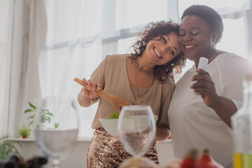 Happy african american woman holding salad near mother with smartphone during thanksgiving...