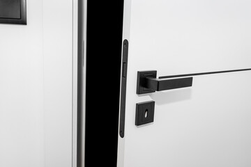 Modern white door with matte black handle and magnetic locks, lock with insert key.