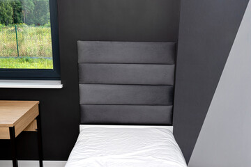 A bed in a modern boy room in black and white colors, visible forest outside the window.