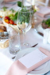 Menu mockup with glasses, flower fork, knife served for dinner in restaurant with cozy interior