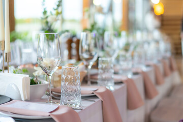 Wine glasses, flowers, fork, knife served for dinner in restaurant with cozy interior