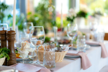 Wine glasses, flowers, fork, knife served for dinner in restaurant with cozy interior