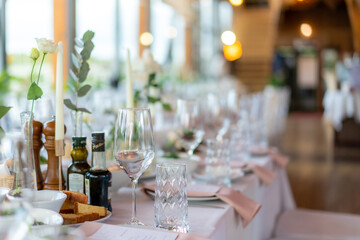 Wine glasses, flowers, fork, knife served for dinner in restaurant with cozy interior