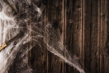 Spider web on wooden background with knives. Halloween banner. Copy space. Selective focus.