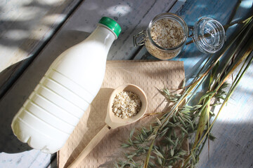 Oat milk in a bottle and oat stalks on a background with sun glare. The concept of an alternative to animal milk. Vegan product