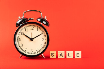 alarm clock on a red background, time for shopping. Black Friday
