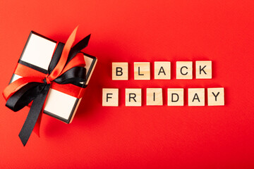 gift box lettering black friday on a red background with copy space.
