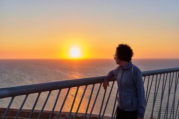 Woman looking at sunrise over the sea on a coast line