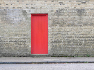 Bright red door embedded in grey brick wall with copy space