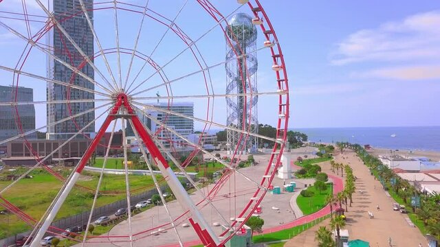 Drone footage. Aerial photography of a drone flying around a Ferris wheel on the seashore of the city of Batumi, Georgia, Adjara. The drone flies over the statues of Ali and Nino in love.