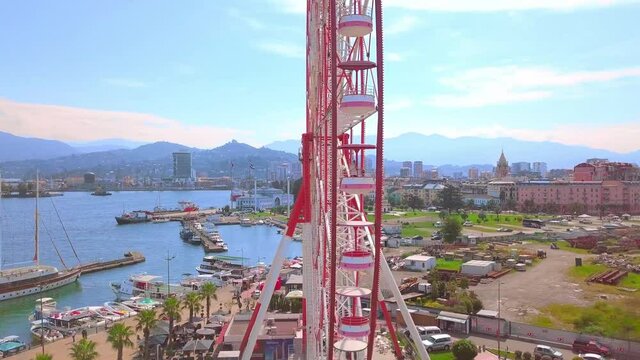Drone footage. Aerial photography of a drone flying around a Ferris wheel on the seashore of the city of Batumi, Georgia, Adjara. The drone flies over the statues of Ali and Nino in love.