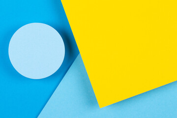Abstract geometric light blue and yellow color background. Round shape platform podium for product display on blue and yellow paper background. Top view