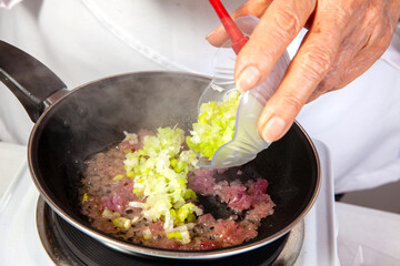 Preparation of the traditional Colombian hogao or criollo sauce (salsa criolla) made of onion, tomato, peppers and cilantro