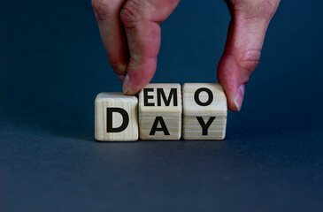 Demo day symbol. Businessman turns wooden cubes with concept words 'demo day' on a beautiful grey...