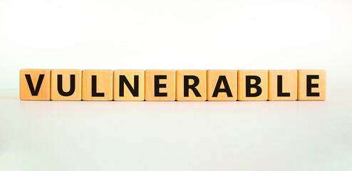 Vulnerable symbol. The word Vulnerable on wooden cubes. Beautiful white table, white background. Business and vulnerable concept. Copy space.