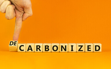 Carbonized or decarbonized symbol. Businessman turns a wooden cube and changes words 'carbonized' to 'decarbonized'. Orange background, copy space. Business, Carbonized or decarbonized concept.