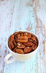 A Cup Filled with Dried Pecan Nuts Isolated on Pale Blue Wooden Table