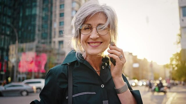 Close up portrait of a lovely modern woman in the middle of a city street. Happy mature lady, business woman, equal rights and feminism concept. Slow motion