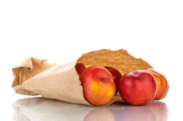 Several juicy organic yellow-red plums with paper bag, close-up, isolated on white.