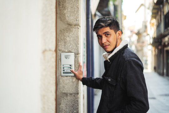 Latino Man Ringing A Building Doorbell