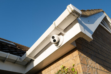 Newly installed, dome type night and day colour CCTV camera attached to the eaves of a private bungalow. One of a number of cameras to monitor a cul-de-sac. - obrazy, fototapety, plakaty