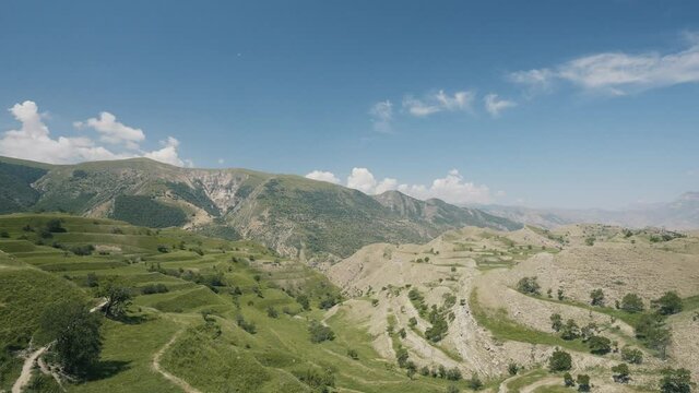 Aerial view of amazing landscape with beautiful valley on a sunny day. Action. Flying above summer mountains on blue cloudy sky background.