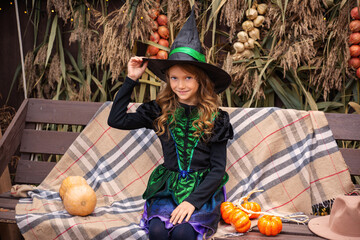 Preparing for Halloween. A girl dressed as an evil witch dress and a big hat. She's in a good mood. Kids love Halloween.