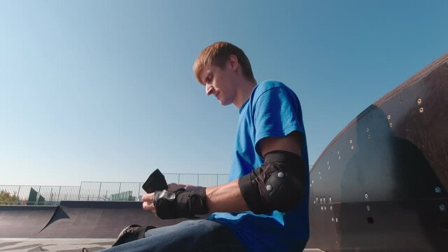 Man puts on hands protection in skate park