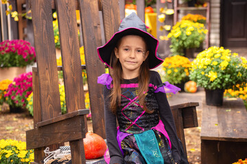 happy child girl wearing witch costumes in autumn halloween holiday