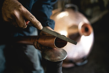 An old man,a worker in a workshop for making cauldrons for an alcohol distillation.