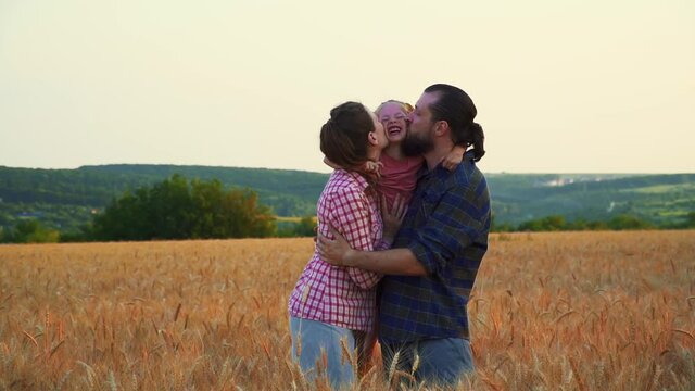 Family having fun in the field at sunset. Summer wheat harvest. Happy family father, mother and child daughter launch a kite on nature at sunset. Run and laugh. Smile and hug.